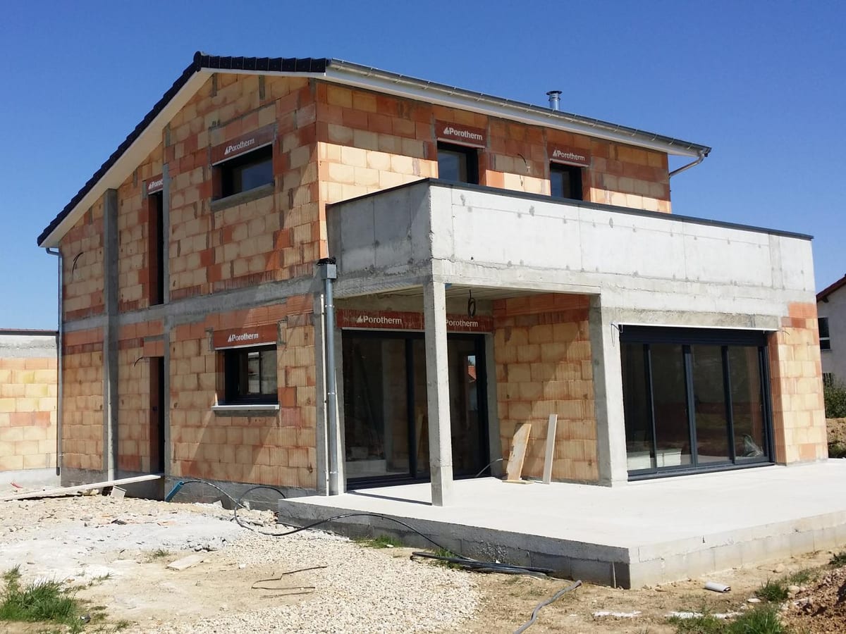 Chantier de construction en briques avec banches de coffrage sous ciel bleu