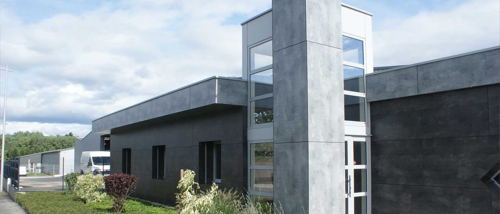 Bâtiment d'activité neuf en zone artisanale, façade en panneaux béton et hall d'entrée vitré